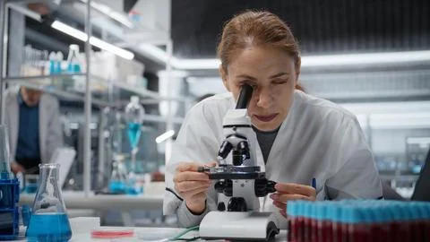 Molecular biologist using compound microscope for detailed cellular analysis Stock Photos