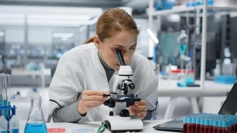 Molecular biologist using compound microscope for detailed cellular analysis Stock Photos