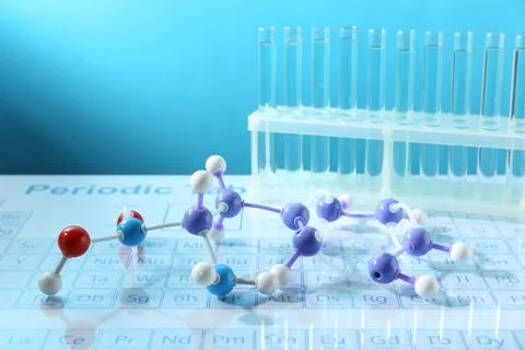 Molecular model and test tubes on periodic table against light blue backgroun Stockfoto's