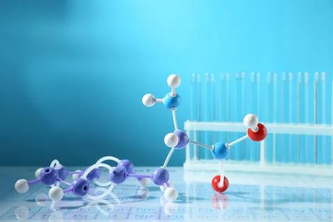 Molecular model and test tubes on periodic table against light blue backgroun Stockfoto's