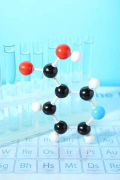 Molecular model and test tubes on periodic table against light blue backgroun Stock Photos