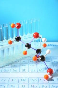 Molecular model and test tubes on periodic table against light blue backgroun Foto stock