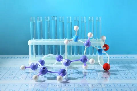 Molecular model and test tubes on periodic table against light blue backgroun Foto stock
