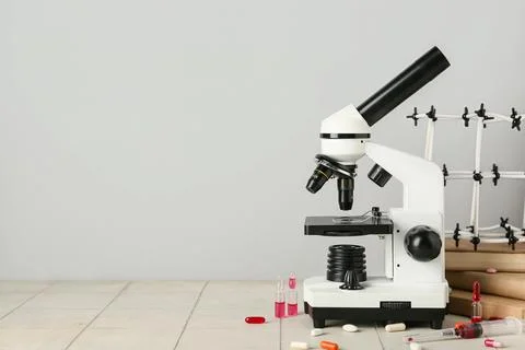 Molecular model with microscope, books, ampules and pills on tile against gre Photos