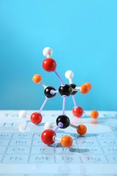 Molecular model on periodic table against light blue background Stockfoto's