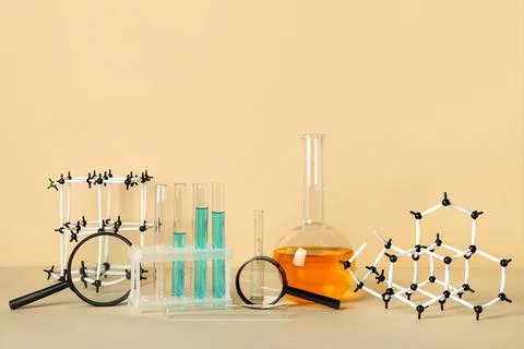 Molecular models with magnifiers, test tubes and flask of samples on beige ba Stock Photos