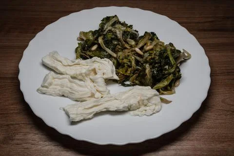Molise Stracciata with a side of pan-fried escarole and pine nuts Stock Photos