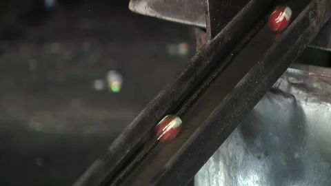 Molten Glass Marbles Rolling Down a Metallic Conveyor - Close Up - 4K Stock Footage 292806350
