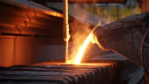 Molten metal pours from a large container into molds Vidéo 313598611