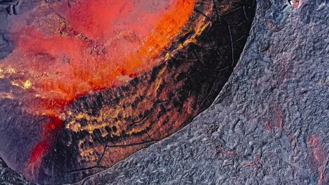 Molten volcanic lava flowing through dark cooling basalt crust creates intense Stock Footage 343696362