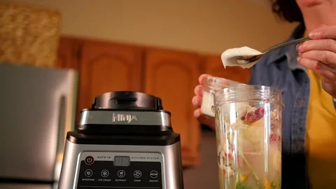 Mom adding yogurt to a nutritious, green smoothie. Stock Footage 138333033
