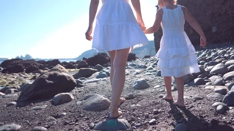 Mom and daughter in beautiful white dresses hold hands and go barefoot on large Stock Footage 101750053