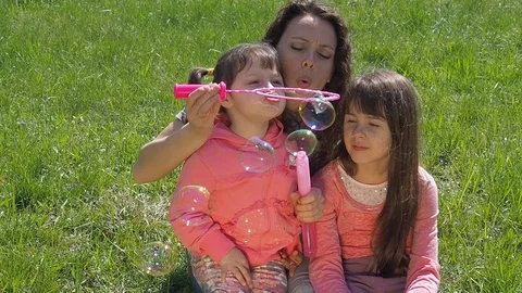 Mom and daughter blow bubbles. Family in the park. Stock Footage