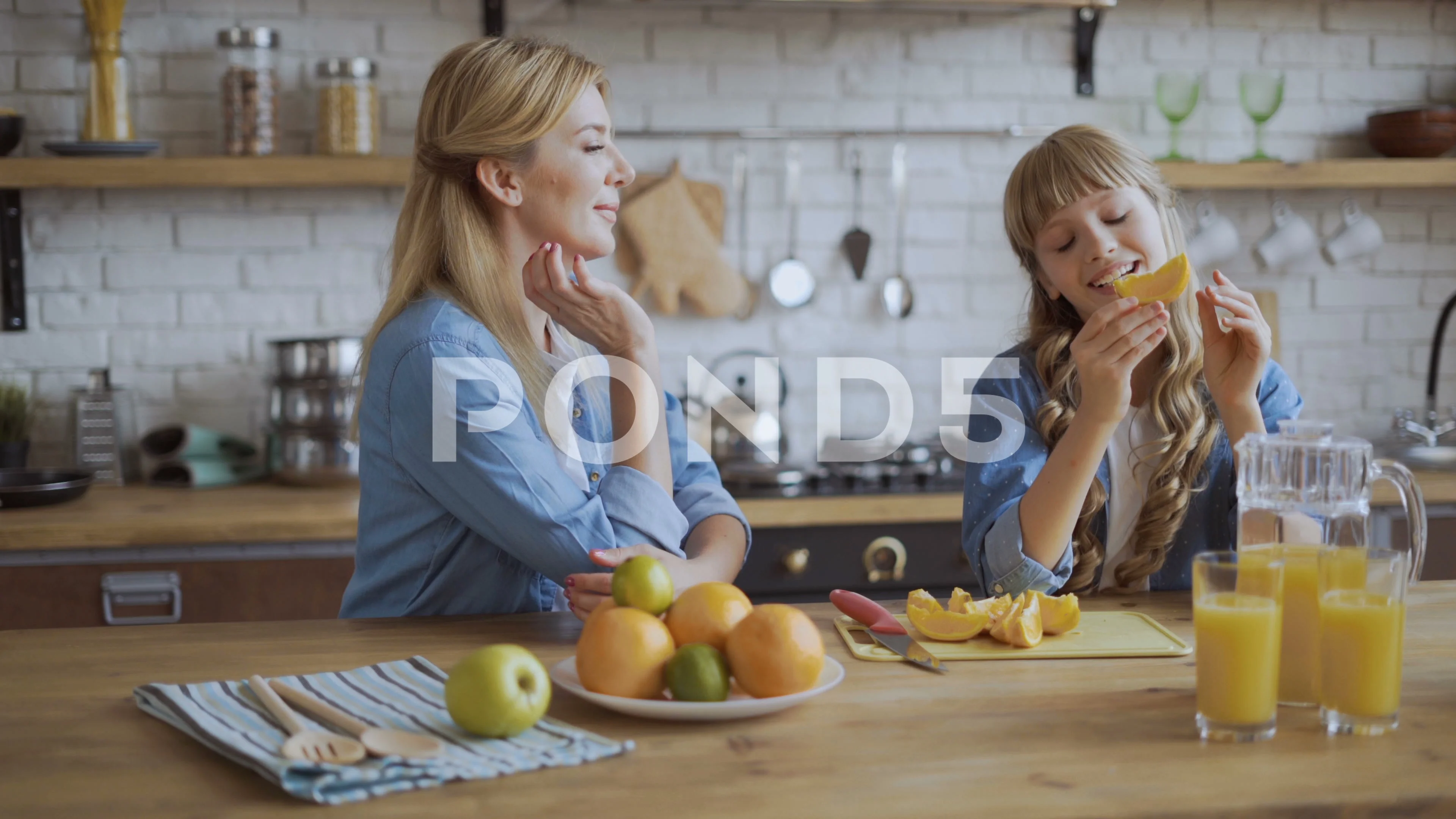 Mom and daughter eat oranges while sitting in the dining room. Juicy ripe  orange