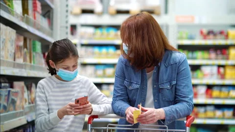 Mom and daughter in masks doing shopping in supermarket Stock Footage