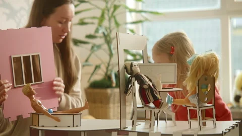 Mom and daughter in process of assembling wooden toy house, playing with dolls Stock Footage 236551678