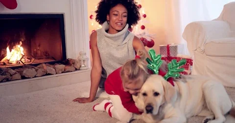 Mom and daughter in sweaters play with pet dog Stock Footage