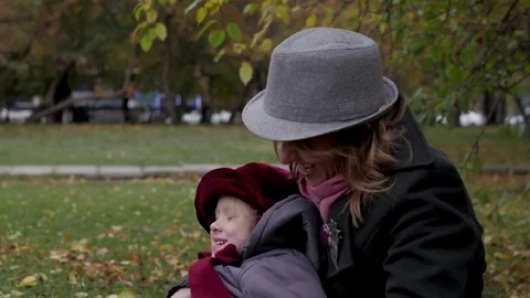 Mom and daughters play in the park, lie on a rug, throw leaves Stock Footage