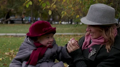 Mom and daughters play in the park, lie on a rug, throw leaves Stock Footage