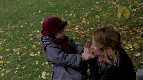 Mom and daughters play in the park, lie on a rug, throw leaves Stock Footage
