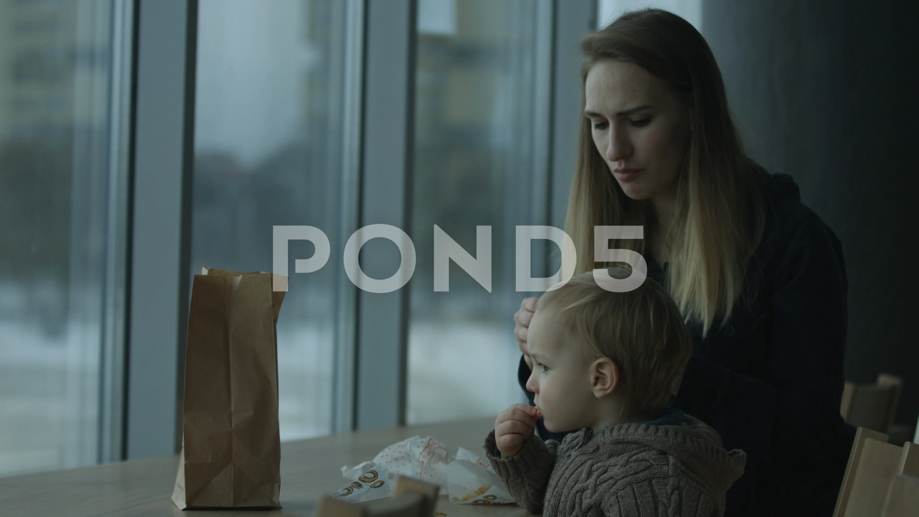 Mom and son eating fast food meal in a cafe, a large window.