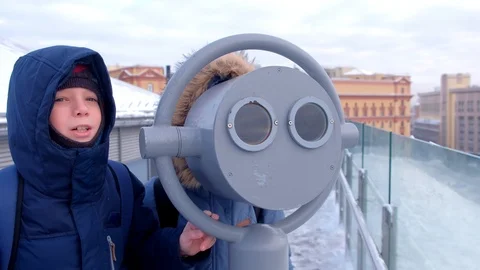 Mom and son looking through binoculars on roof of building in city in winter. Stock Footage 119010372