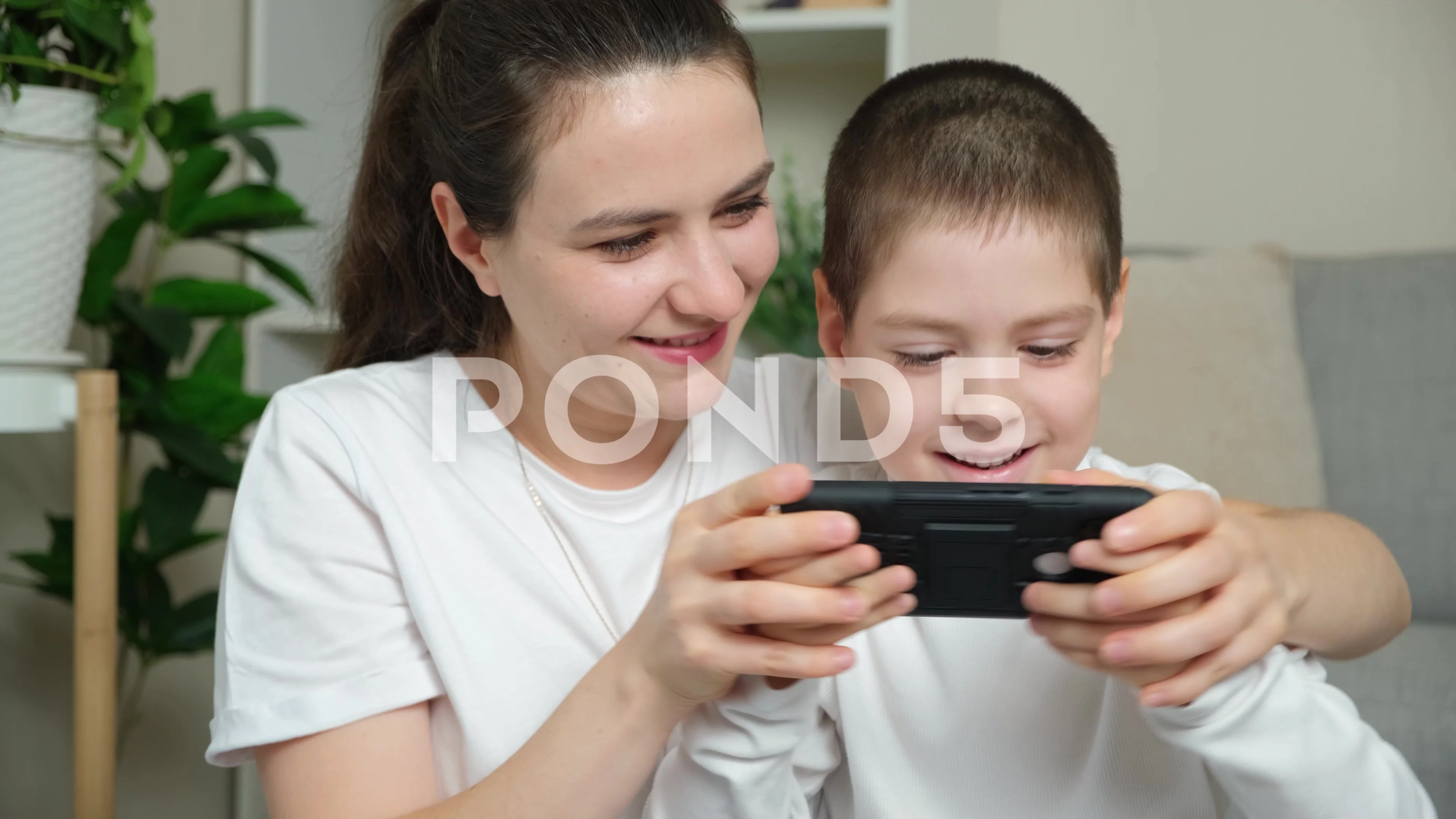 Mom and son playing a video game together on a smartphone. Fun pastime,  common