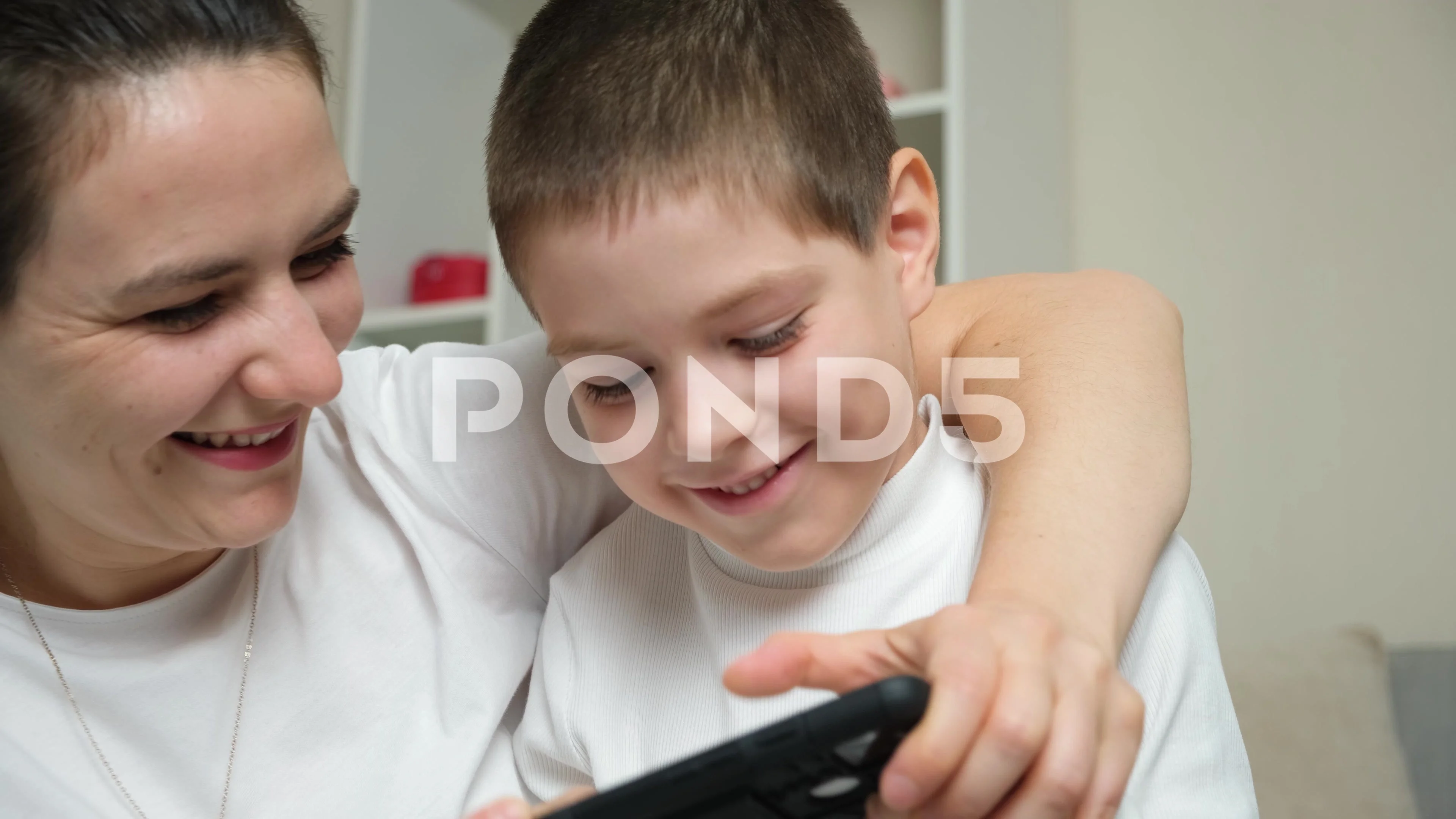 Mom and son playing a video game together on a smartphone. Fun pastime,  common