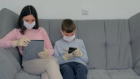 Mom and son using gadgets at home isolation on coronavirus pandemic quarantine. Video stock 128987004