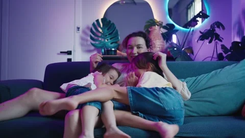 Mom and Two Daughters Different Ages are Sitting on the Sofa and Watching TV Stock Footage 255592018