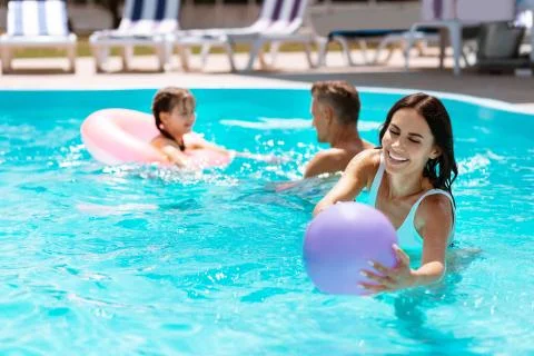 Mom catching the ball in pool while having fun together Stock Photos