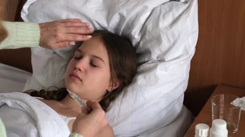 Mom checking temperature of sick child girl with thermometer and her hand Stock Footage 317380435