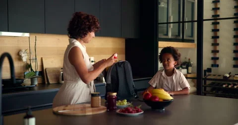 Mom, child and backpack in kitchen for school, morning routine and packing lunch Stock Footage 301025878