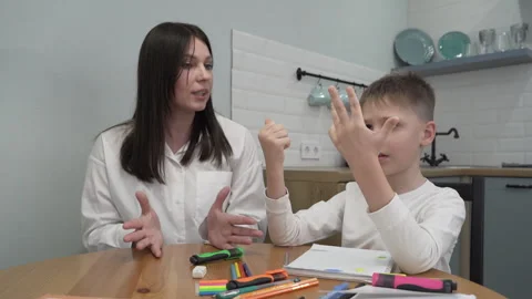 Mom comes up with a math problem for her son sitting at the table child counts Stock Footage 261060844