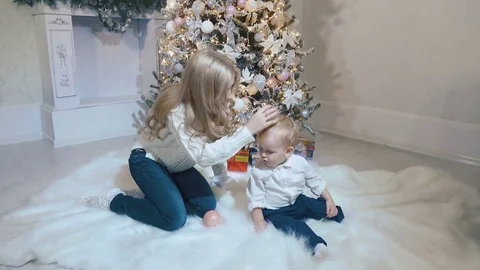 Mom corrects the hat to a small child near the tree Stock Footage 75245933