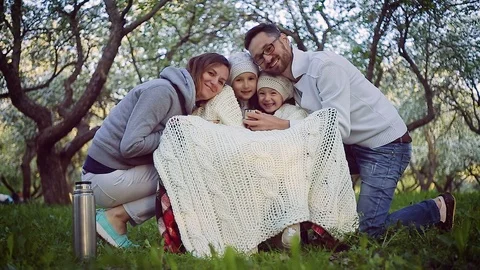 Mom, dad and two daughters drink tea in the spring garden Stock Footage 101983853