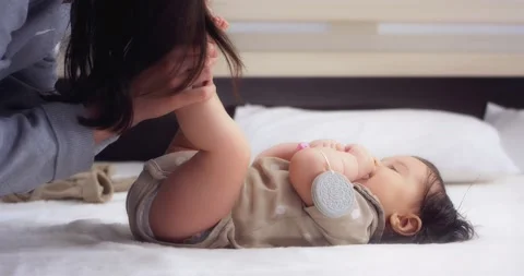 Mom does exercises for the baby's legs, kisses small feet. Stock Footage 186512872