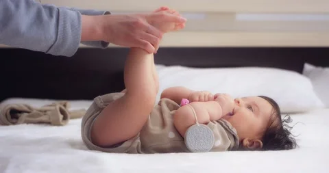 Mom does exercises for the baby's legs, kisses small feet. Stock Footage 186518227