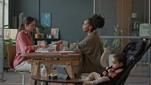 Mom Doing Paperwork with Colleague while Toddler in Stroller Watching Tablet Stock Footage 310952895