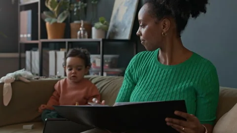 Mom Doing Report next to Her Baby Son Watching Tablet PC at Office Stock Footage 310951712