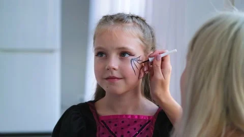 Mom draws a web and a spider on the child's face. Stock Footage 164388317
