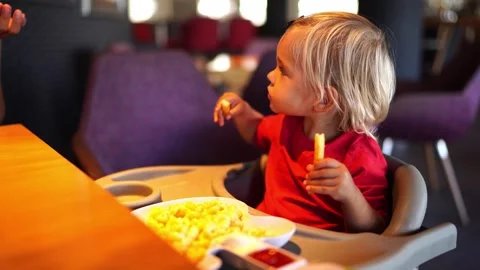 Mom eats pasta from a plate next to a little girl eating french fries Stock Footage 283727983