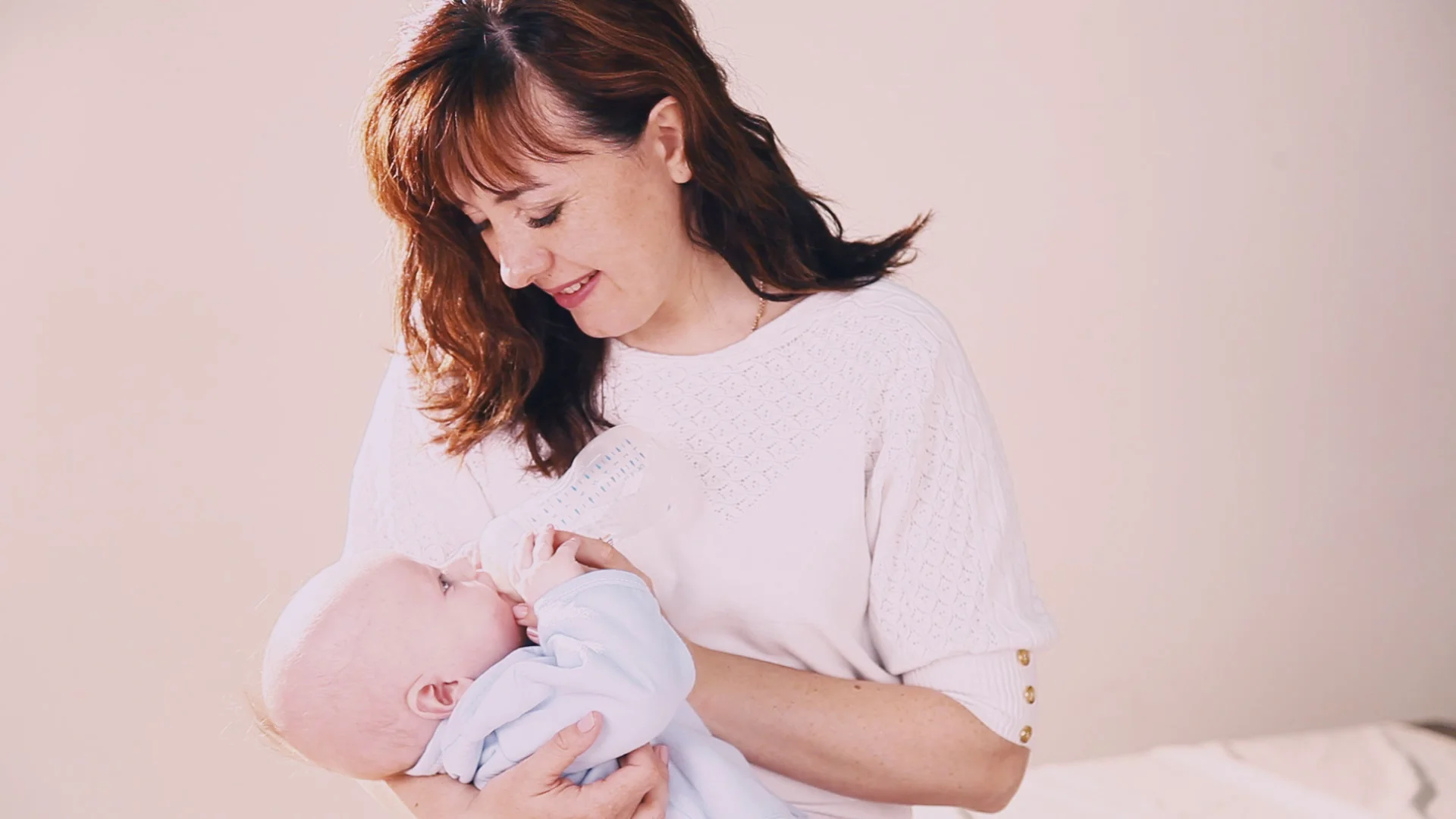 mom is feeding the baby milk from a bottle