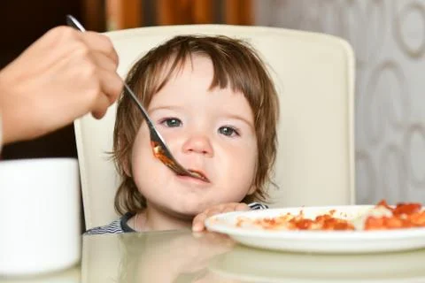 Mom feeds the baby with a fork. Mother feeds the baby. Healthy eating for kid Stock Photos