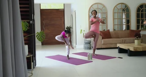 Mom guiding child in tree pose, child copying and learning balance on purple Stock Footage 336059096