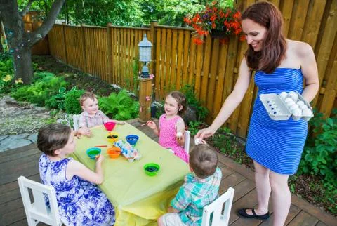 Mom Handing Out Easter Eggs to Paint to Her Children Stock Photos