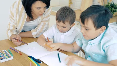 Mom helping two sons to perform drawing markers in the album. Stock Footage 118523809