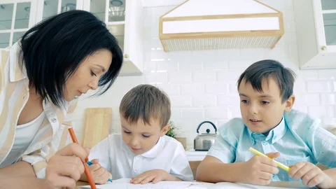 Mom helping two sons to perform drawing markers in the album. Preschool Stock Footage 118525115