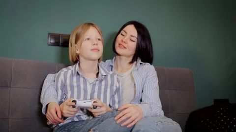 Mom hugging her child while daughter plays video game. Video game console Stock Footage 265104833