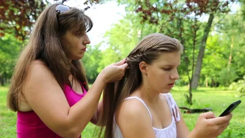 Mom makes the braid of the eldest daughter Stock Footage 92153432